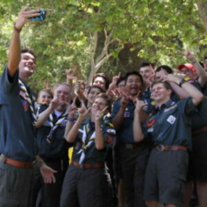 Group photo of a group of Venturing scouts taking a selfie in the woods. They are smiling and throwing "peace" signs